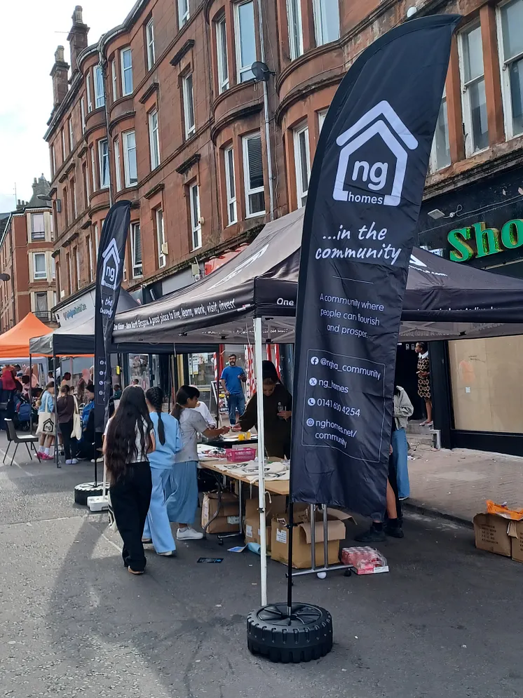 ng homes branded flags and gazebo with residents in front of festival stalls