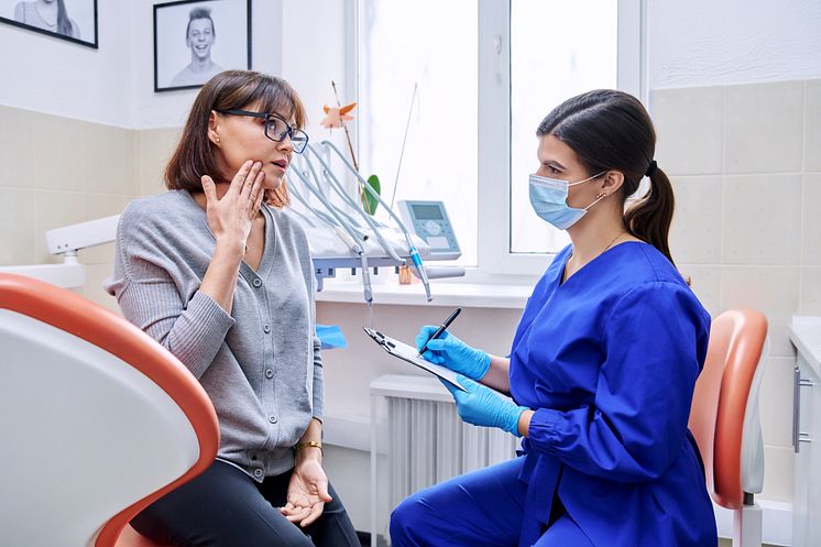 55416116-dental-office-visit-female-patient-talking-to-doctor