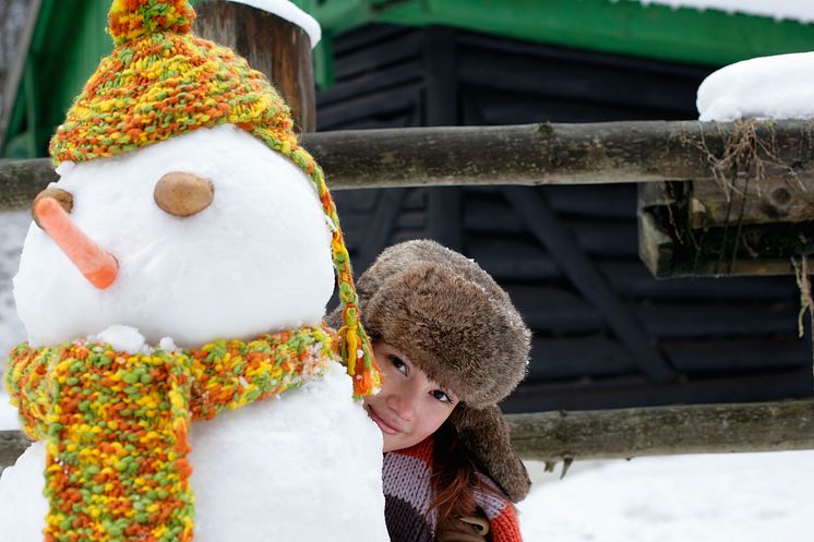 Junge Frau mit Fellmütze hinter Schneemann.jpg