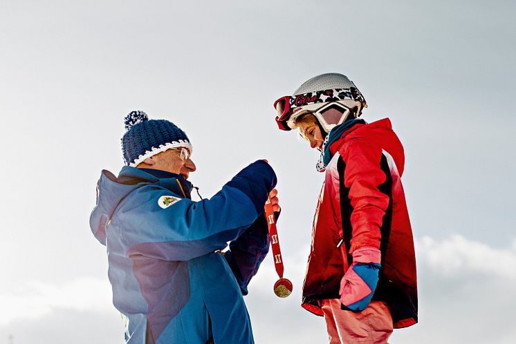 Skischulleiter Noldi Heinz überreicht einem Skischüler eine Medaille, Arosa Skischule, Arosa-Lenzeheide (Graubünden)