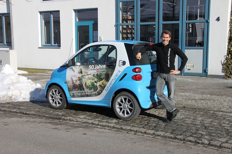 Foto: Mit dem „50 Jahre Jugend forscht E-Smart“ trifft das Patenunternehmen Bayernwerk ehemalige bayerische Preisträger, hier Daniel Gurdan, und lässt diese das Elektroauto signieren.