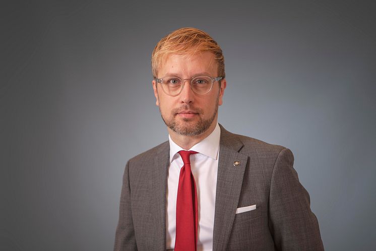 Porträtt på man med glasögon och röd slips. 