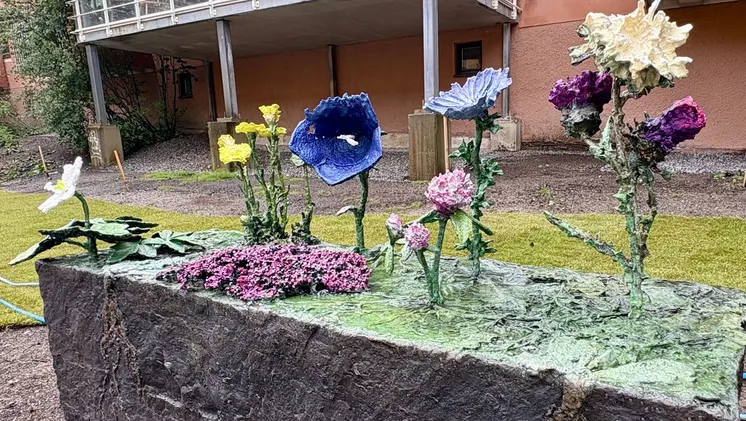 En bronsskulptur föreställande blommorna vitsippa, tussilago, backtimjan, blåklocka, rödklöver, cikoria och vägtistel.