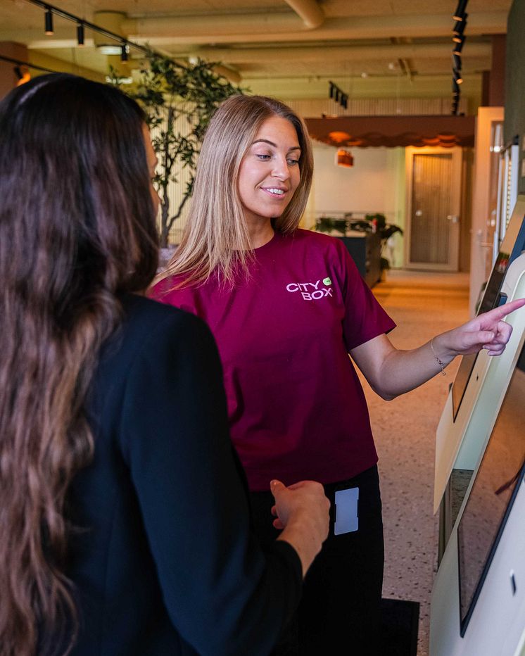 Host helping guest with check-in terminal