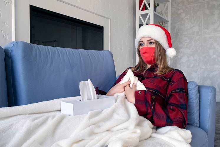 health-cold-holiday-people-concept-sad-sick-young-woman-with-medical-mask-home-young-blonde-girl-red-shirt-christmas-hat-lies-sofa-with-napkins.jpg