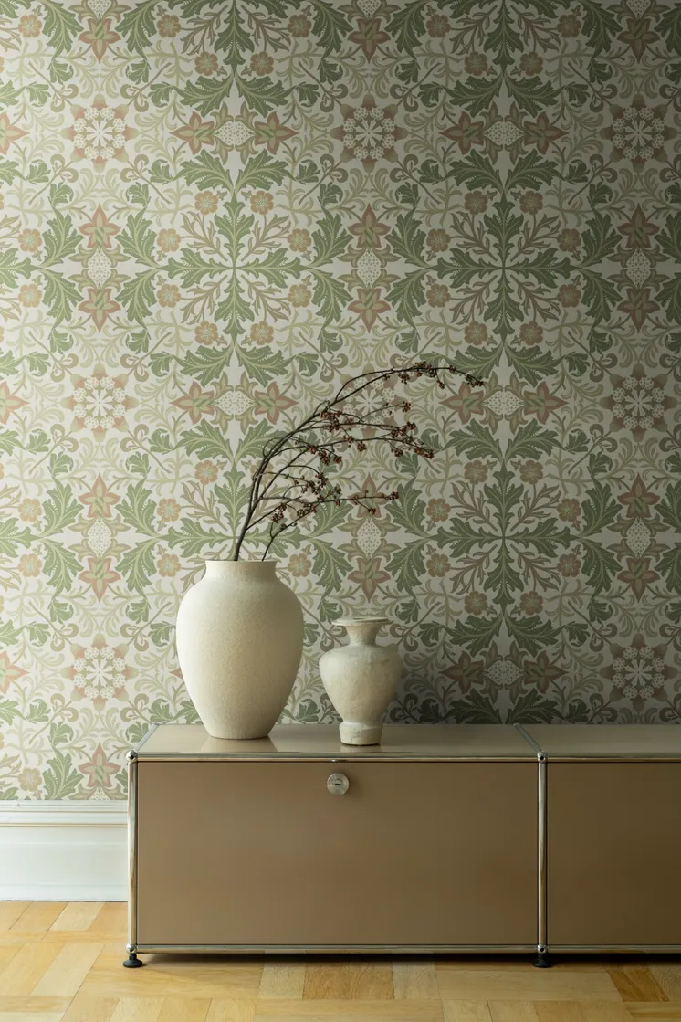Ljus tapet med symmetriskt blommönster i gröna, beige och rost toner, beige skåp och dekorativa vaser.
