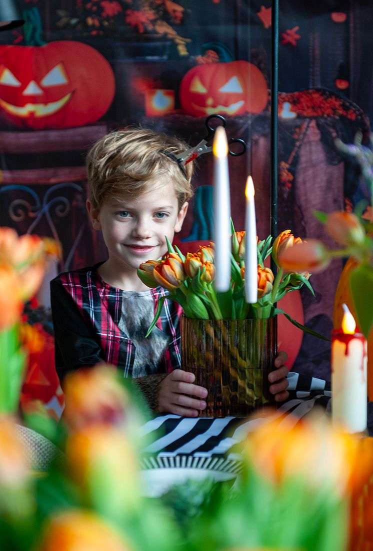 Pojke med tulpaner i vas på halloween