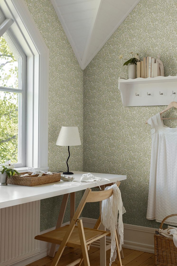 Tapet med blommor och blad i mjuka nyanser av grönt, beige, och havre i en ljus och luftig syhörna.