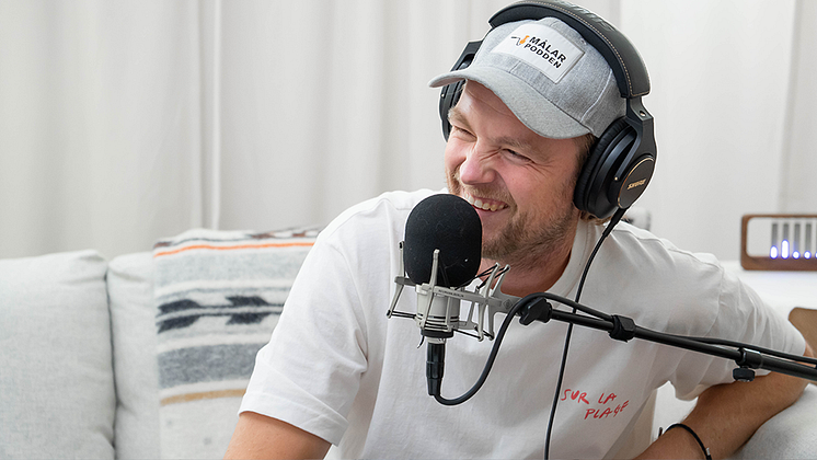 Simon Strömberg skrattar bakom en mikrofon
