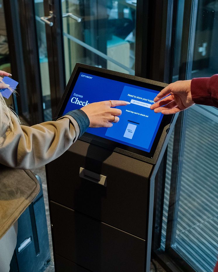 Host helping guest check out via the express check-out machine