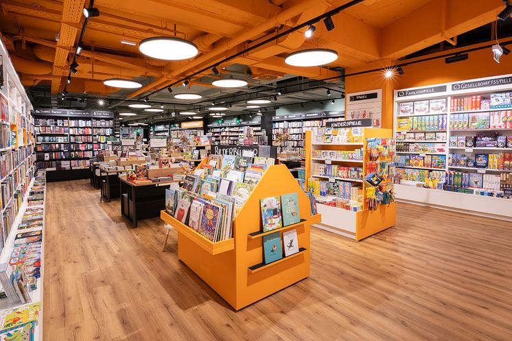 Blick in die Familienwelt der Thalia Buchhandlung Zentrum Simmering mit Regalen voller Bilderbücher, Kinderbücher und Spiele.