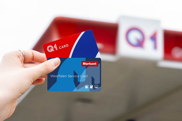 Hand hält Westfalen Service Card und Q1 Card vor einer Q1 Tankstelle