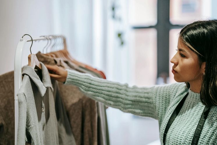 Kvinna i butik tittar på en tröja som hänger på en galge
