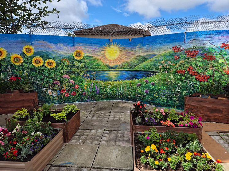 Painted mural with planted garden boxes with flowers.