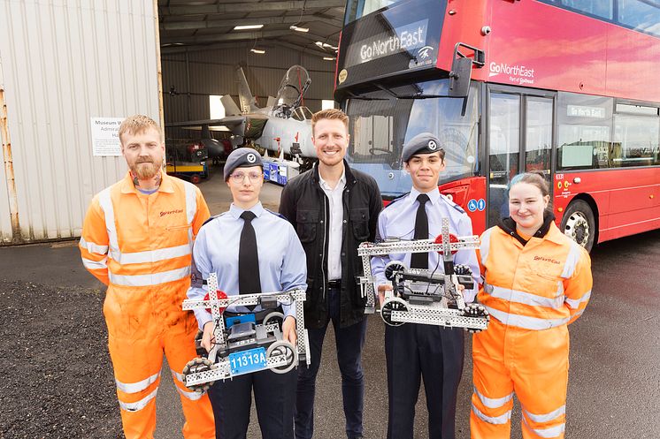 Gateshead cadets with Go North East Engineers and Business Director in front of a bus and plane in aircraft hanger.