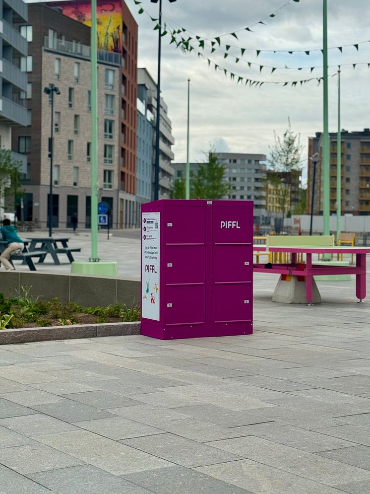En rosa Piffl-box står på ett  torg. Runt omkring finns bordtennisbord, bänkar vilket skapar en aktivitetsyta.