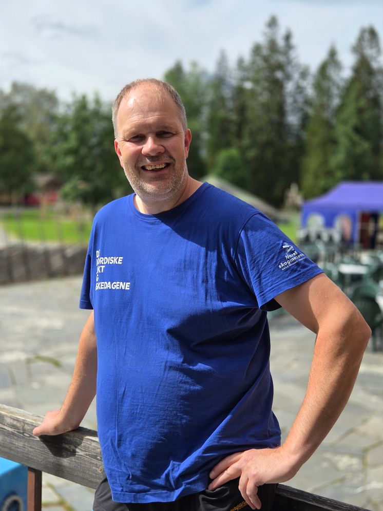 En smilende mann i blå t-skjorte