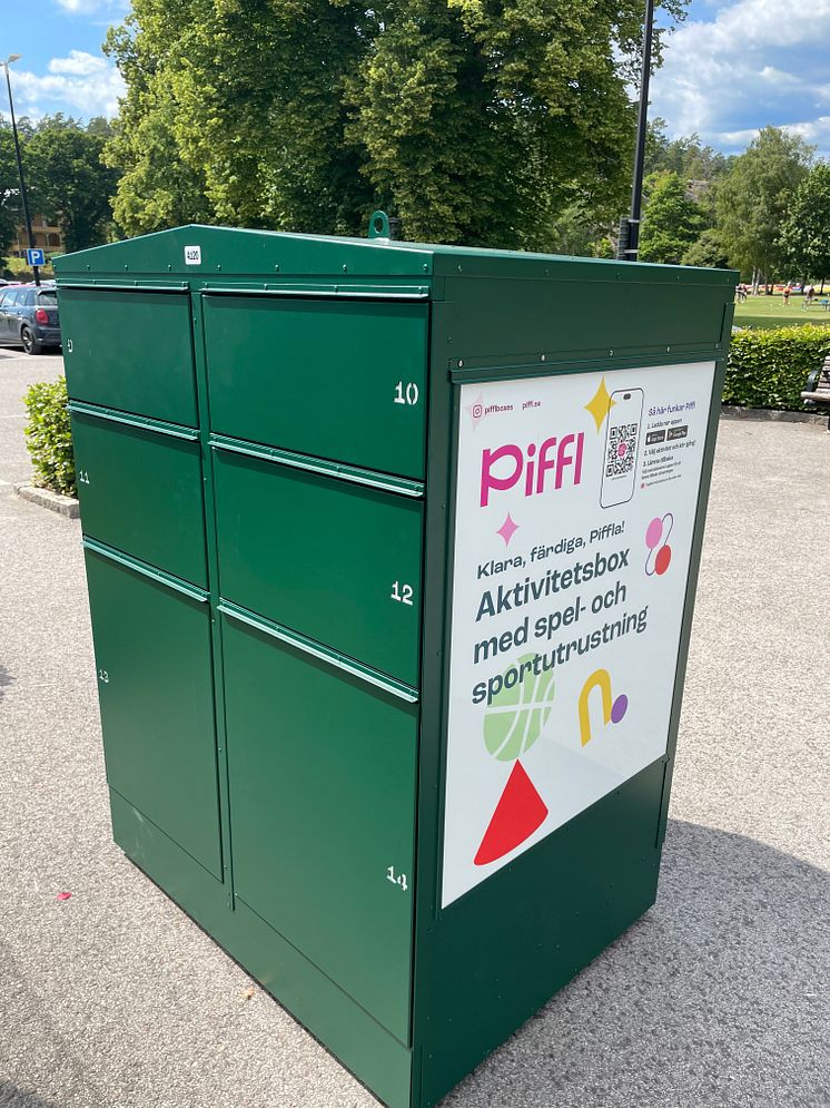 Grön aktivitetsbox från Piffl i Brunnsparken, Ronneby, placerad nära utomhusbadet och stora grön ytor.