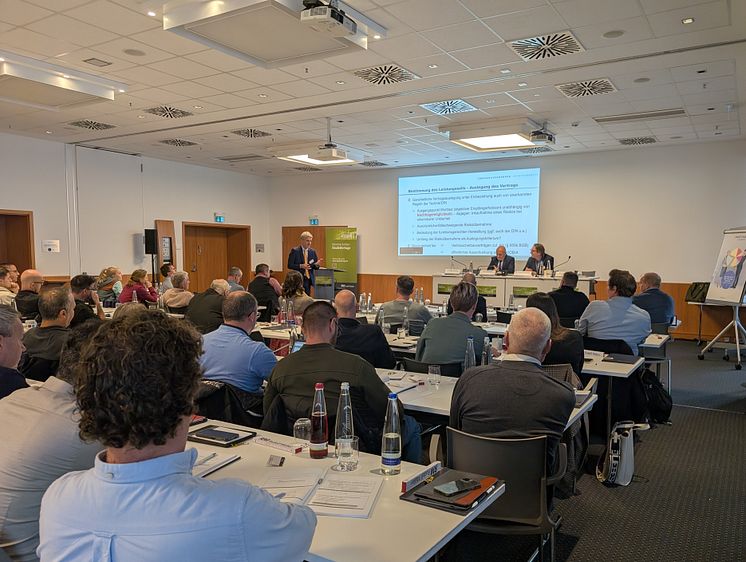 Ein Referent spricht bei den Münchner Bauleitertagen vor einem gut gefüllten Konferenzraum. 
