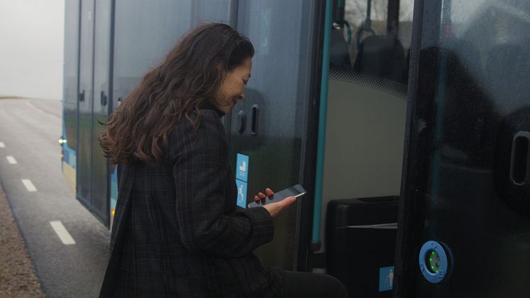 Kvinna går på buss med mobil