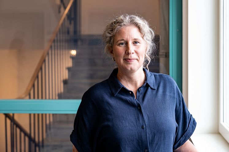 Porträttbild av en person med ett trapphus i bakgrunden.