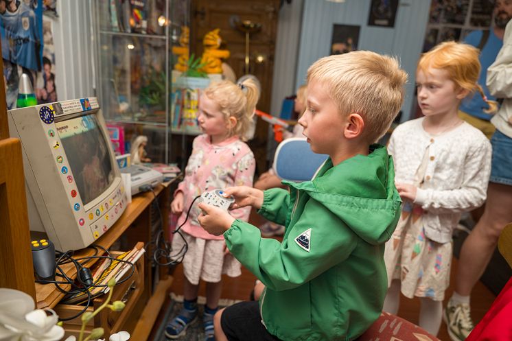 Tre små barn spiller dataspill på en gammel skjerm fra 1990-tallet