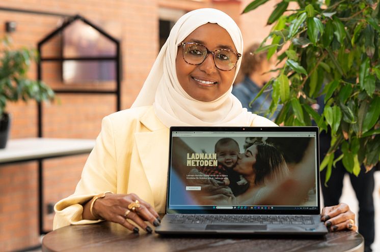 Person kvinna ler glasögon ljus klänning slöja står inomhus laptop visar webbsida