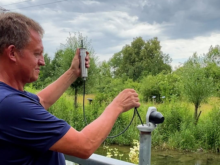 LEW Mitarbeiter setzt einen Inno.Live-Sensor in ein Metallrohr, Auegewässer, Aue