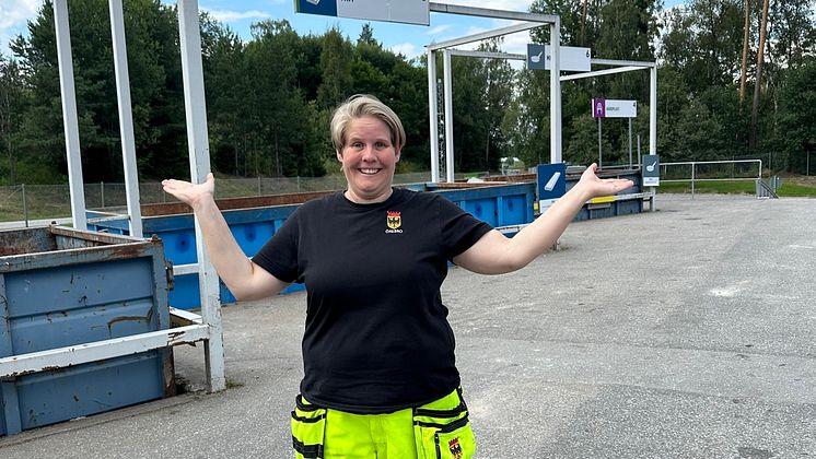 Kvinnlig anställd står framför containrar på återvinningscentral i Örebro kommun