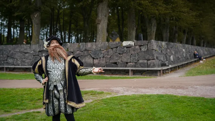 Person i historiska kläder framför en lång bänk