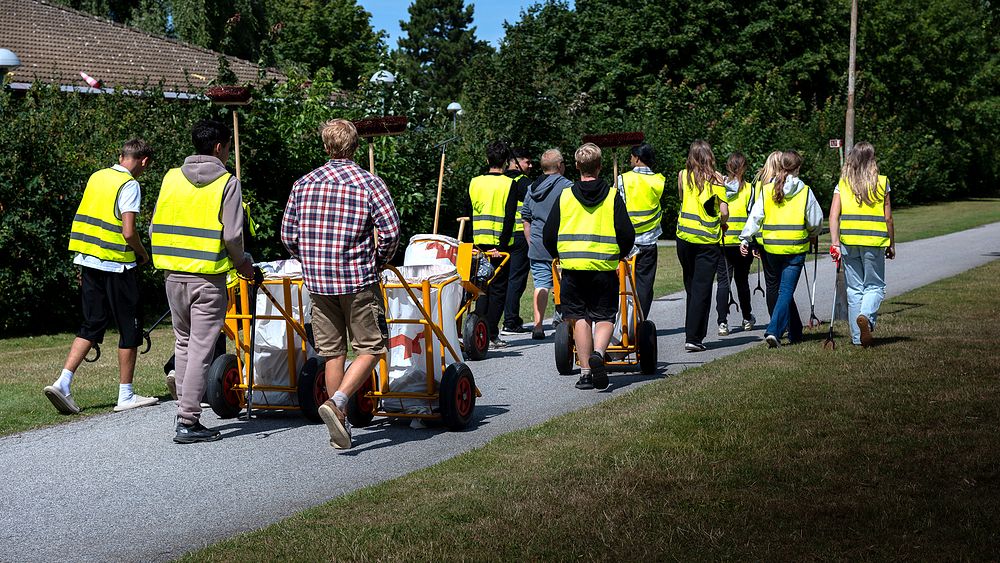 En grupp människor i gula västar som går längs en väg.