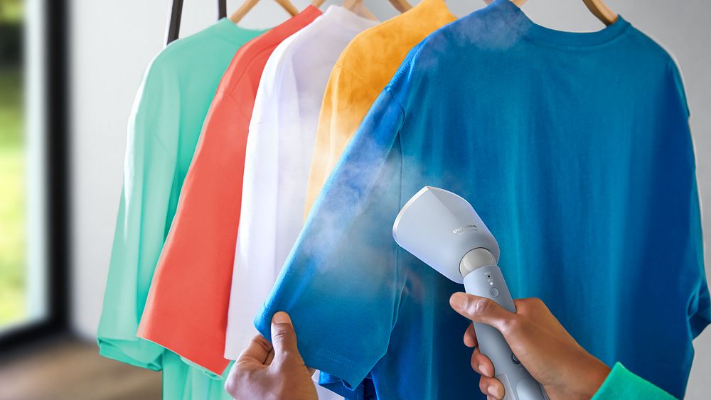 Philips Handhållna Steamer 5000 Series steamar en blå t-shirt som hänger på en galge