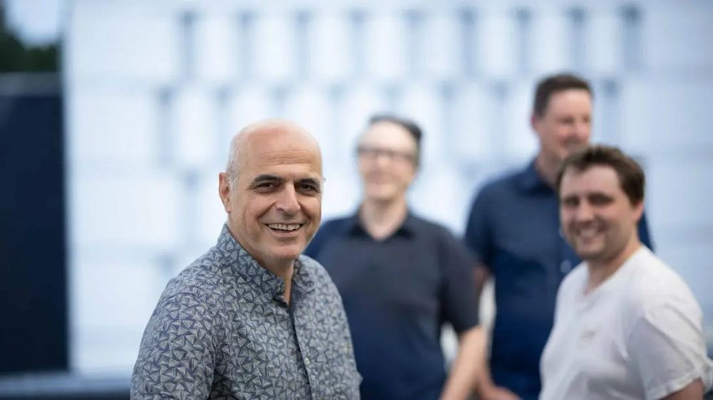 Bilde av 4 menn, en av dem smilende i forgrunnen