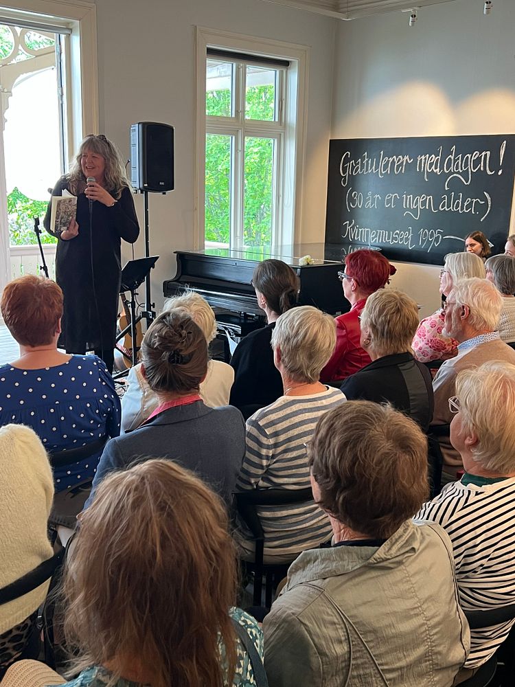 En kvinne snakker i en mikrofon foran et publikum.