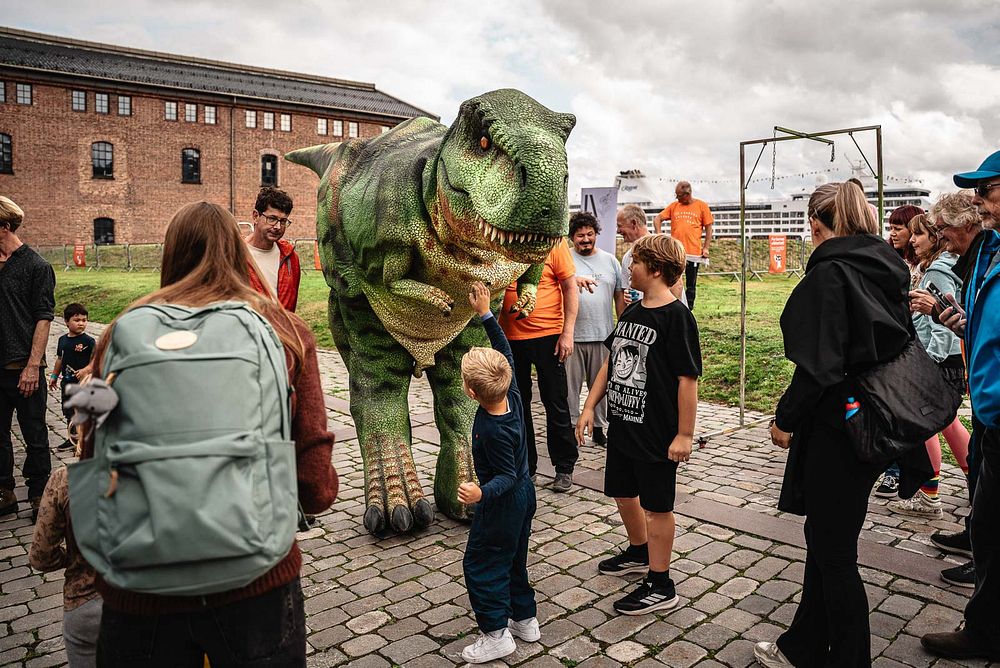 Barn som hilser på dinosaur.