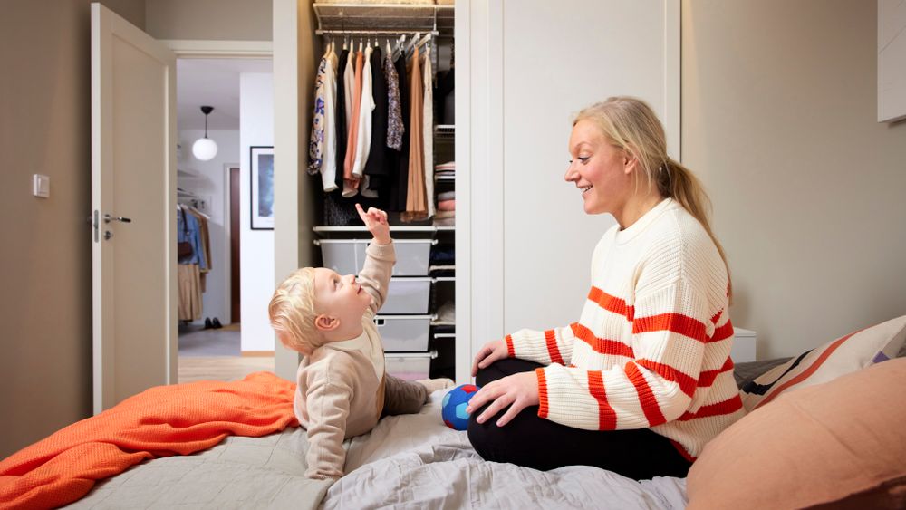 Person arranging clothes in an open hallway wardrobe with mirrored sliding doors.