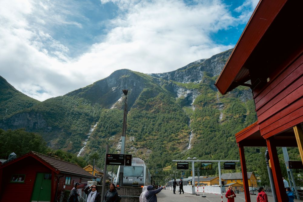 Flåm railway station beneath steep green mountains in western Norway.