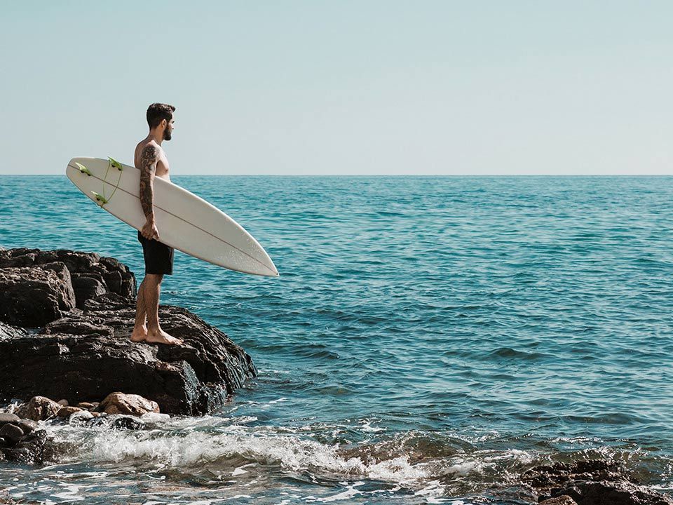 Man with the surfboard on Uluwatu beach