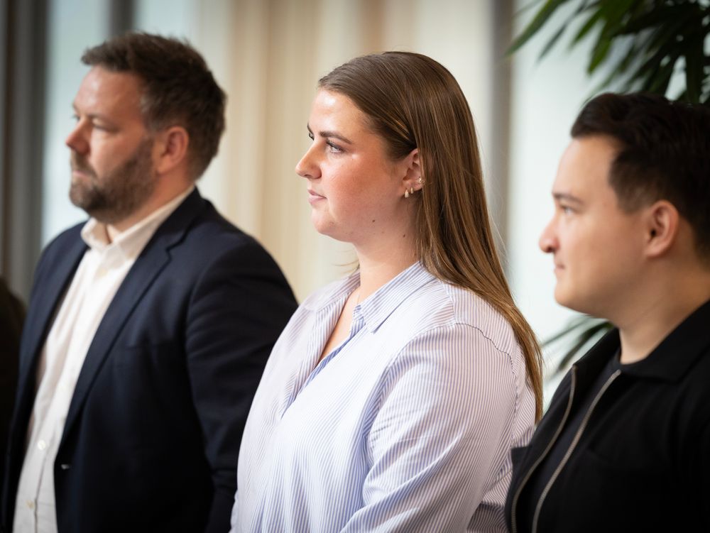 Tre personer står ved siden av hverandre og lytter under signeringen av samarbeidsavtalen.