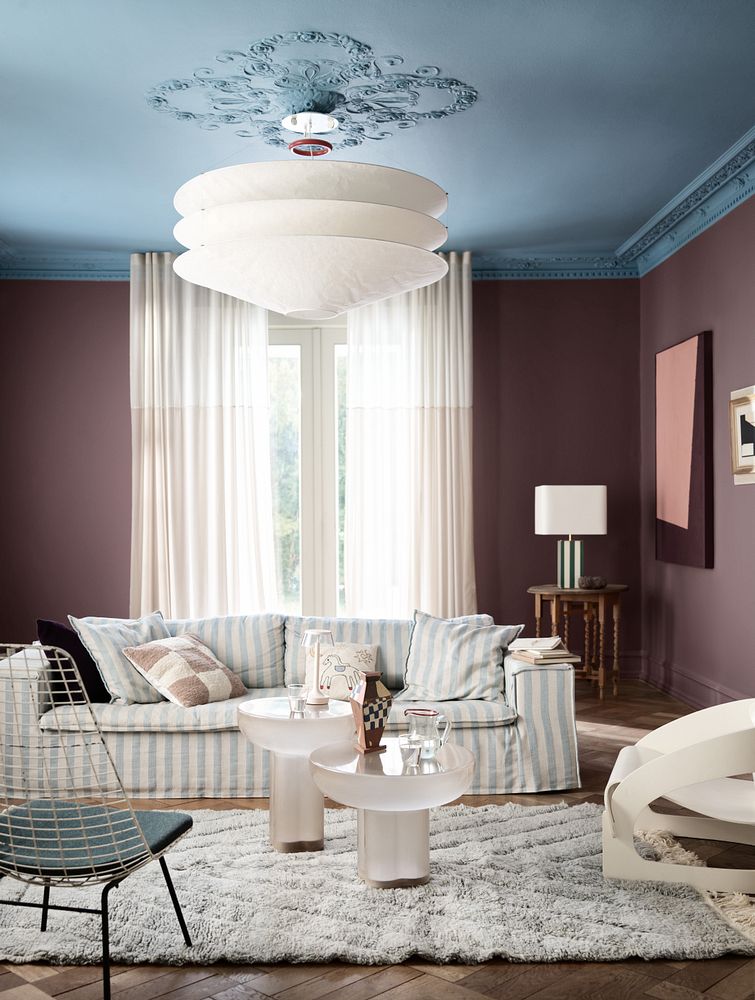Stue med sofa, mykt teppe og sidebord, og rommet er malt i modige kontrastfarger med blått tak i fargen Sama og den dempede plommefargen 2243 Dusty Purple i supermatt finish, begge farger fra Jotun.