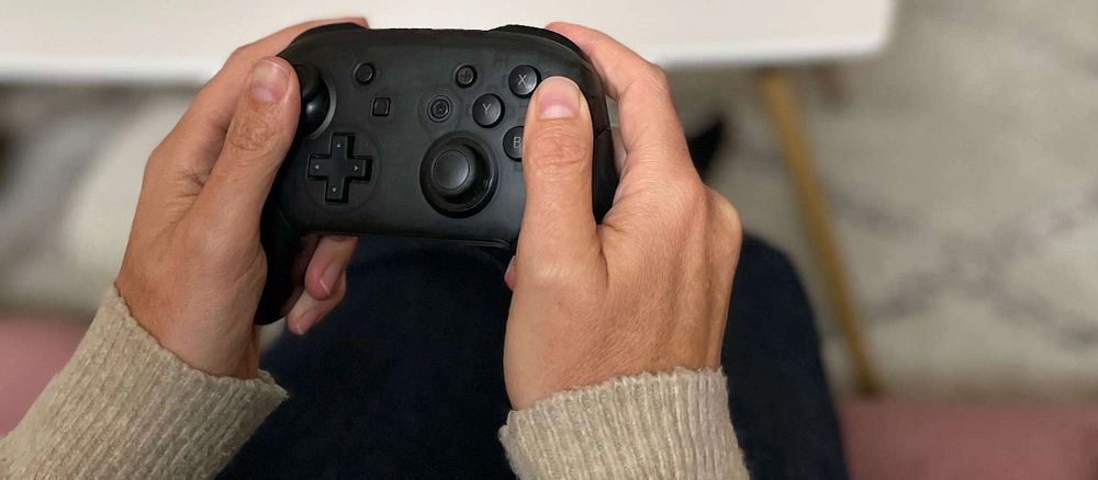 Två händer som håller i en spelkontroll, foto.