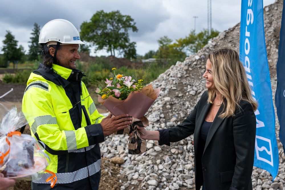 En kvinna ger blommor till en en man i varselkläder.