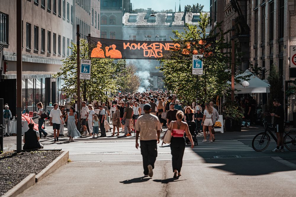 Folkemengde i bygate, med banner som sier Kokkenes Dag.