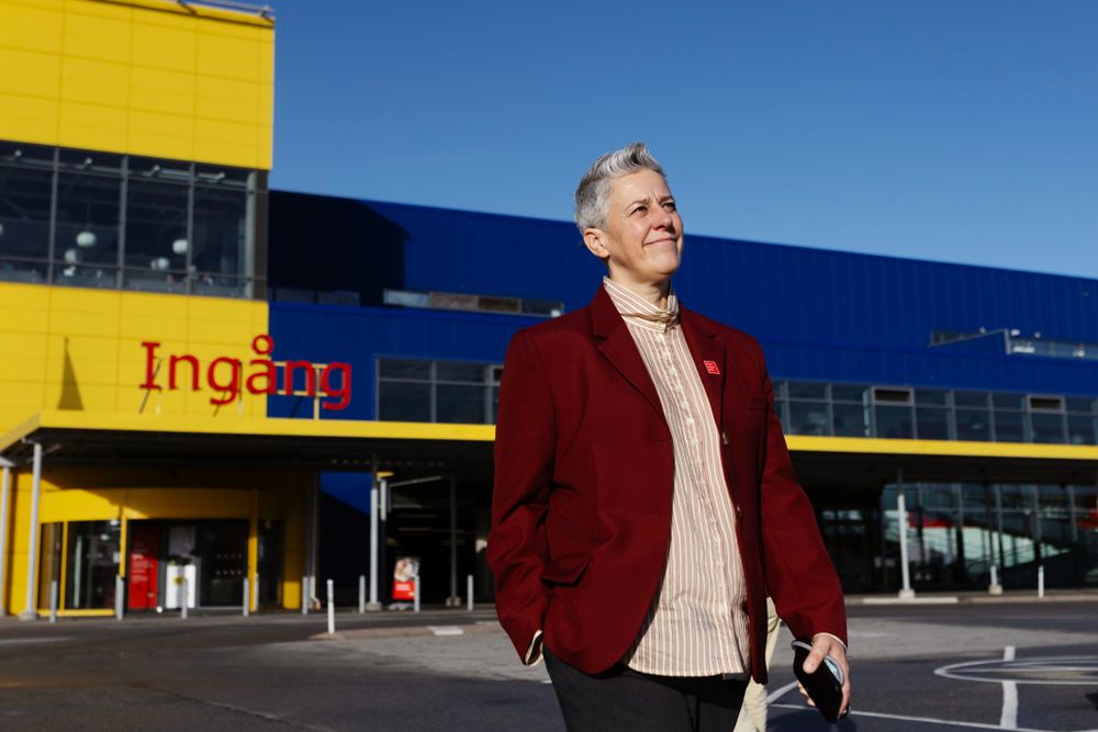 En kvinna med röd kavaj står utanför ett IKEA-varuhus.