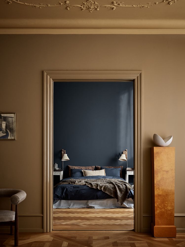 Døråpning til soverom i den dype blåfargen Midnight Blue fra Jotun, med kontrastfargen Spice Brown i det nærmeste rommet.