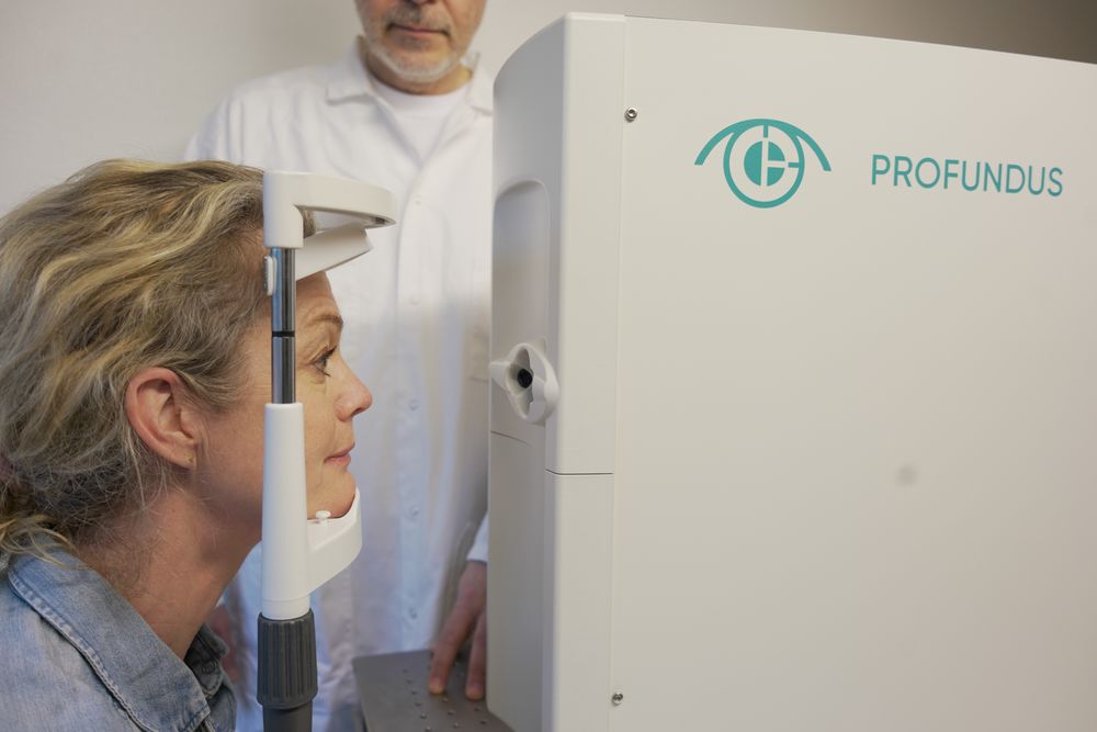 Patient being examined using the Profundus camera, with innovator and engineer Zoran Popović in the background. Photo: Melisha Linnell
