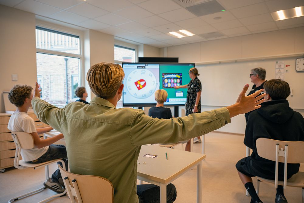 En grupp människor i ett rum med en stor skärm.